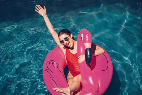 Woman floating on a pink flamingo in a pool